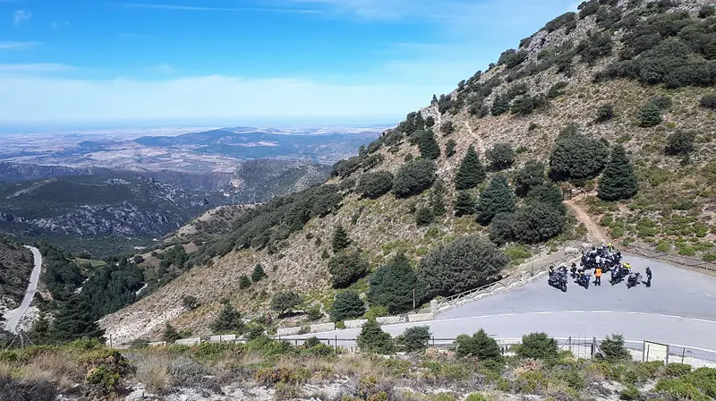 Groep motorrijders met hun motoren in een haarspeldbocht hoog in de Spaanse bergen